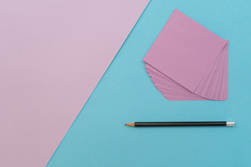 Purple sheets of paper and a pencil on a blue-purple background. Place for text.