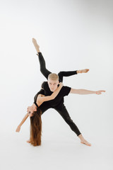 Fototapeta na wymiar Modern Ballet Couple do Dance Lift on Middle Level. Male Dancer Hold Girl Upside Down. High Skill Perfomer in Black Denim and Top Isolated on White Background. Athletic Man Looking at Camera
