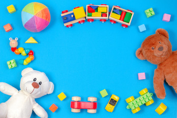 Baby kids toys background. Two teddy bears, wooden train, toy cars, colorful blocks on blue background