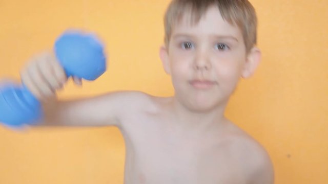 a little boy works out the punches in Boxing with dumbbells in hands makes jab, uppercut