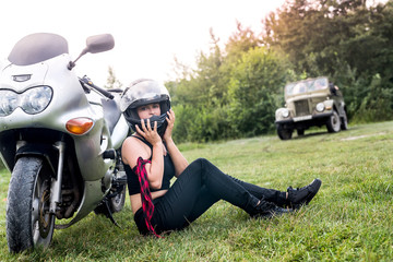 Woman with helmet in her hand, stand near motorcycle