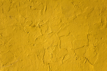old damaged peeling yellow concrete wall with cracks and shadows. rough surface texture