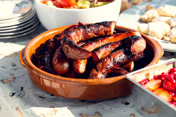 Table at a barbecue party. Grilled sausage in a platter.