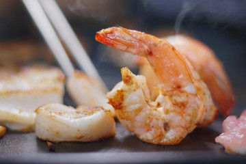 Grilled seafood on hot pan with smoke. Selective focus and free space for text. Healthy food concept.