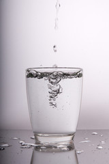 water pouring into a glass on white background