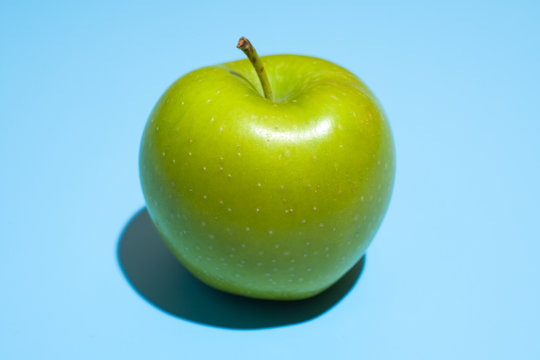 Ripe green apple on blue background. Healthy eating and dieting concept