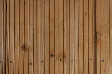 Orange wooden planks with frequent vertical gutter patterns cover the wall indoors. Wooden lining fastened with nails to the base.
