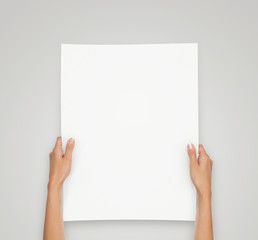 Close up of female hands holding blank paper sheet isolated on gray background with copy space