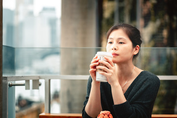 Young woman drinking coffee and eating a delicious muffin cake in cafe,