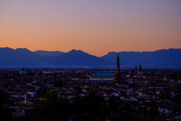 Obraz premium wide panorama during the sunset of the city of Vicenza and the famous monument called Basilica Palladiana with the tall Clock Tower. Vicenza, Veneto, Italy - April 2019