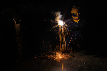 A craftman is welding with workpiece steel.Working person About welder steel Using electric welding machine There are lines of light coming out and safety equipment in factory industry..