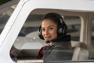 Young Woman Pilot With Headset Looking Through The Cockpit Window