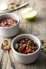 Healthy breakfast.Two bowls of muesli with oats, nuts and dried fruits - apples, resins, pumpkin seeds and almonds on wooden table. Top view. Rustic style.