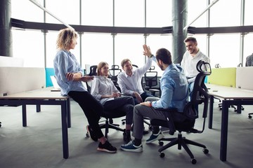 Fototapeta premium High-five! cheerful young business people giving high-five while their colleagues looking at them and smiling.