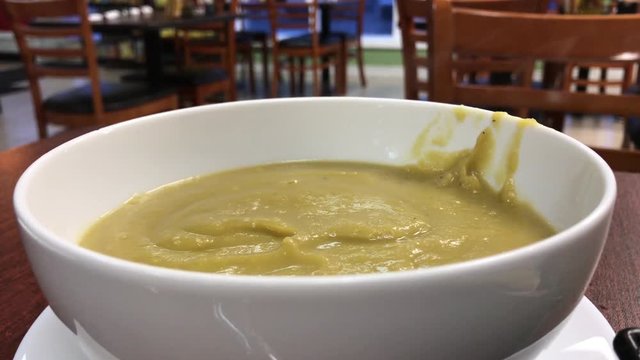 White ceramic bowl containing steaming green split pea soup