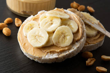 Peanut butter and banana on rice cakes, healthy, dietary food. Black background.