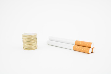 Several cigars and a stack of coins on white background. Economic expenditure.