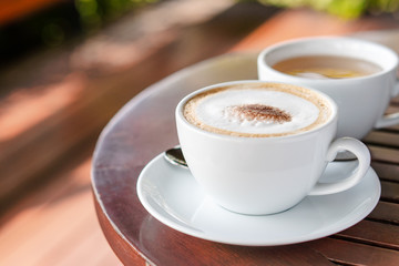 Hot coffee and hot tea place on the wooden table in early morning with copyspace, white cup and silver spoon.