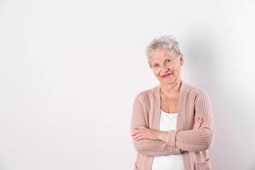 Portrait of grandmother in stylish clothes on light background, space for text