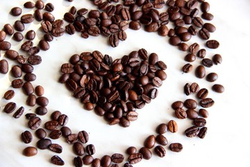 roasted heart-shaped coffee beans on the table, selective focus. a handful of coffee beans in the shape of a heart, after roasting on the table, close-up