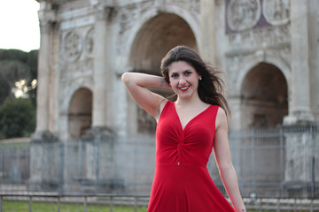 Pretty young girl in red dress in front of Colosseum, Rome, Italy. Rome symbol.