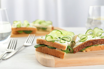 Wooden board with traditional English cucumber sandwiches on table. Space for text