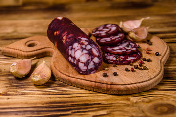 Cutting board with sliced salami sausage and garlic on a wooden table
