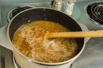 Onion Soup boiling in large pot on electric range.
