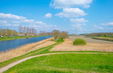 Canal in a residential area field below a blue sky in sunlight in spring