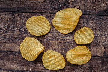crispy potato chips on wooden background. chips started