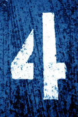 Number 4 in stencil on grungy metal wall in navy blue tone.