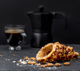 Slice of a sweet cake on a dark table with a coffee cup an spot