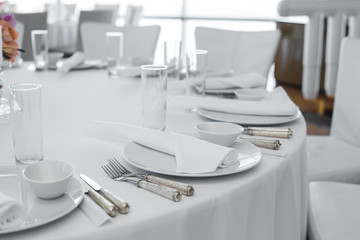 served table in the restaurant. clean white dishes layout on a white tablecloth