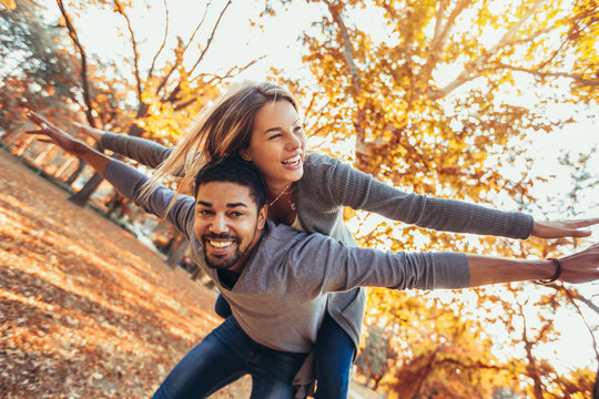 Young Mixed Couple Walking In The Autumn Park