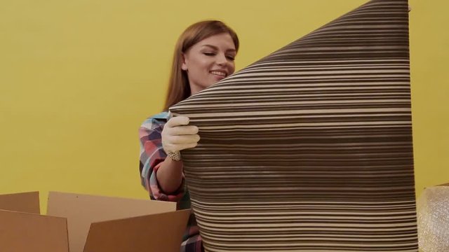 A young woman moves and picks up wallpaper for repair