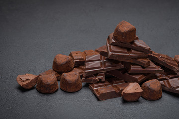 Dark or milk organic chocolate pieces, cocoa powder and truffle candies on dark concrete backgound