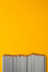 colored pencils arranged in a chaotic line on yellow background