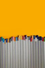 colored pencils arranged in a chaotic line on yellow background