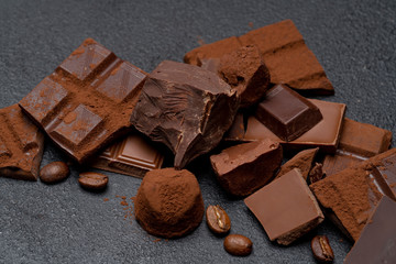 Dark or milk organic chocolate pieces, cocoa powder and truffle candies on dark concrete backgound