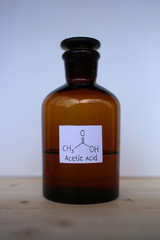 Acetic acid in a bottle of dark glass. Organic acid which is used in organic synthesis as a reagent, a solvent, and a preservative as a food additive.