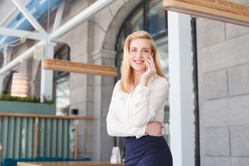 Fototapeta premium Beautiful young woman financial analyst or manager chatting with smartphone and smiling during office break.