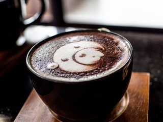 Cup of coffee latte and bear face bubble aet on wood table