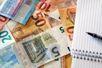 Contabilidad y finanzas, billetes de euro y cuaderno en blanco.