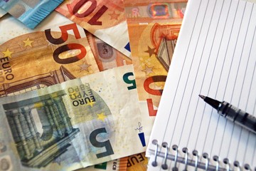 Contabilidad y finanzas, billetes de euro y cuaderno en blanco.
