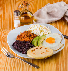 Venezuelan breakfast of arepa, fried egg, black beans, mechada meat, white cheese and avocado