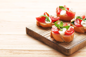 Bruschetta with mozzarella, tomatoes and basil leafs on wooden cutting board