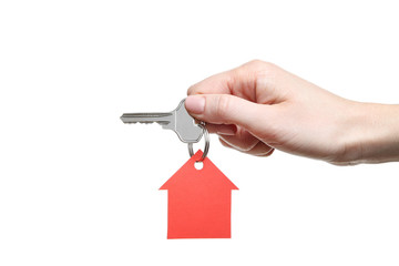Female hand holding silver key with paper house on white background