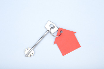 Silver key with paper house on grey background
