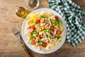 Pasta salad with vegetables and tuna on wooden table. Top view