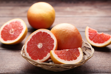 Ripe grapefruits in basket on brown wooden table